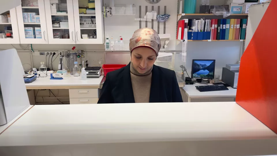 En kvinna ser ner på sin arbetsbänk i labbet. Hon ser koncentrerad ut.