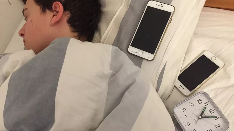 bild på tonåring som sover med mobilen i sängen