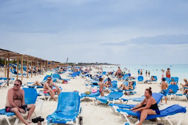 Strand full med människor som solbadar. Foto: Mostphotos
