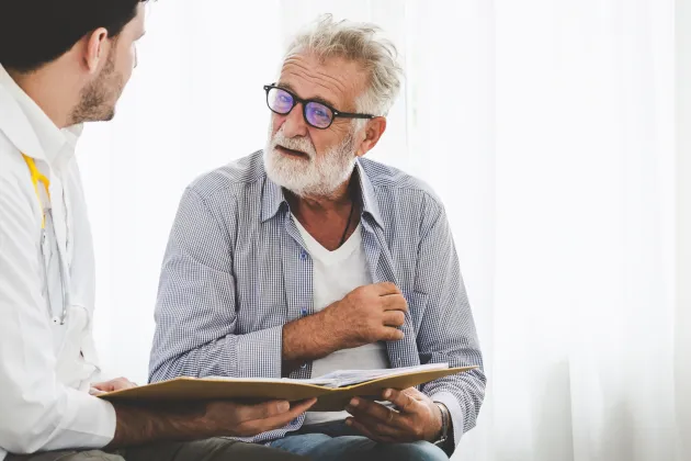 Äldre man blir intervjuad av läkare. Foto: iStock