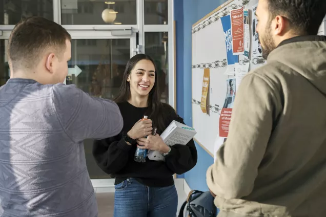 Studenter vid entré och anslagstavla. Foto.