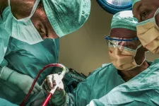 Tre vårdpersonal klädda i gröna operationskläder opererar. Patienten ej i bild. 