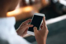 En person sedd bakifrån håller i mobiltelefon i händerna framför sig. Foto: iStock