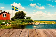 Bild av skärgårdsmiljö, röd stuga med vita knutar. 