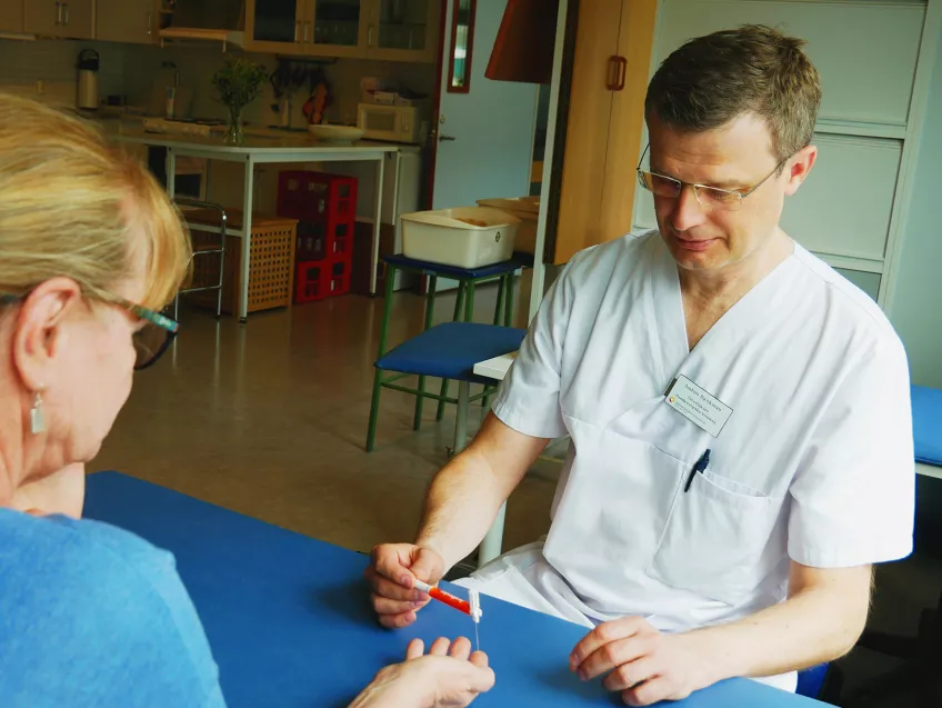 Handkirurgen Anders Björkman genomför en klinisk undersökning på en patients hand. Foto.