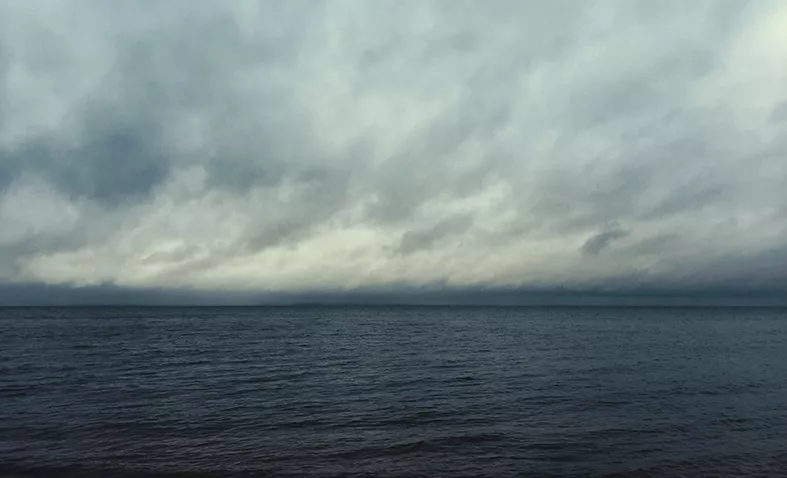 Foto på molnig sky över en grå havshorisont.