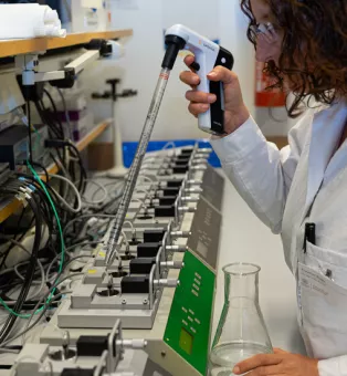 Kvinna arbetar vid laboratoriebänk. Foto.